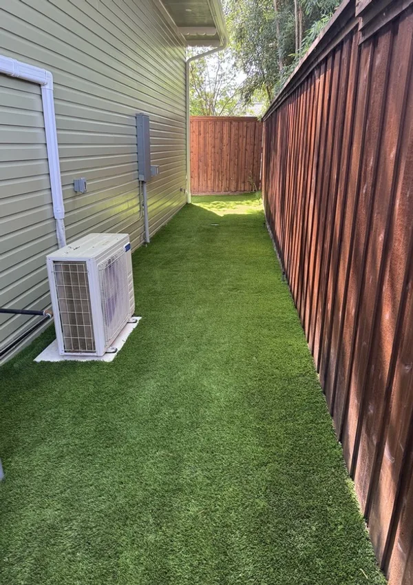 Artificial turf side yard standing tall and lush after professional grooming and infill replenishment