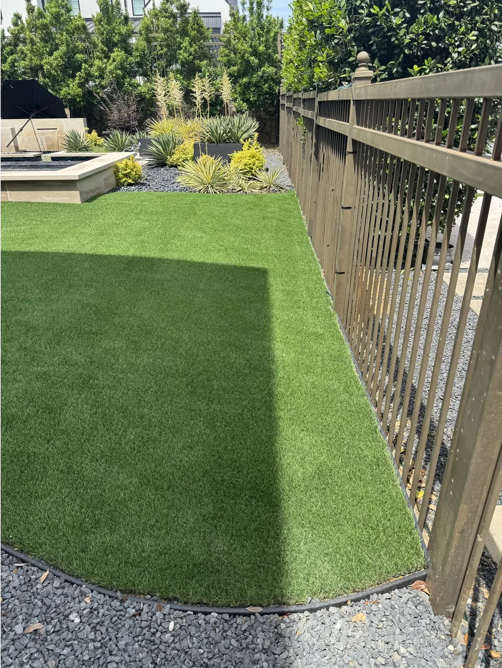 Immaculate artificial turf beside a backyard water feature after professional cleaning